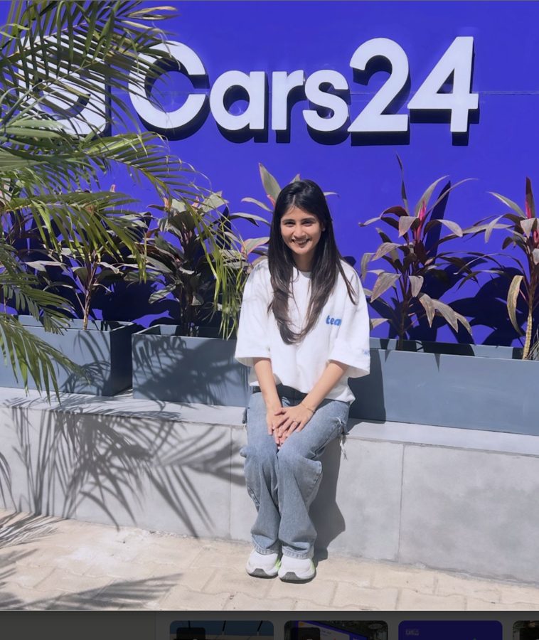 Prachi sitting in front of the Cars24 sign